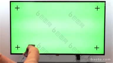 妇女手与电视遥控器切换频道上的绿色屏幕电视观点与luma哑光